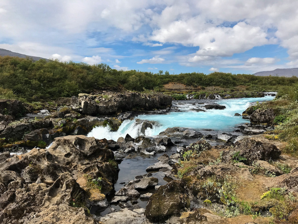 Fluss mit türkisfarbenem Wasser ergibt sich in einen kleinen Wasserfall