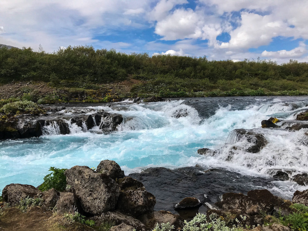 Fluss mit türkisfarbenem Wasser ergibt sich in einen kleinen Wasserfall