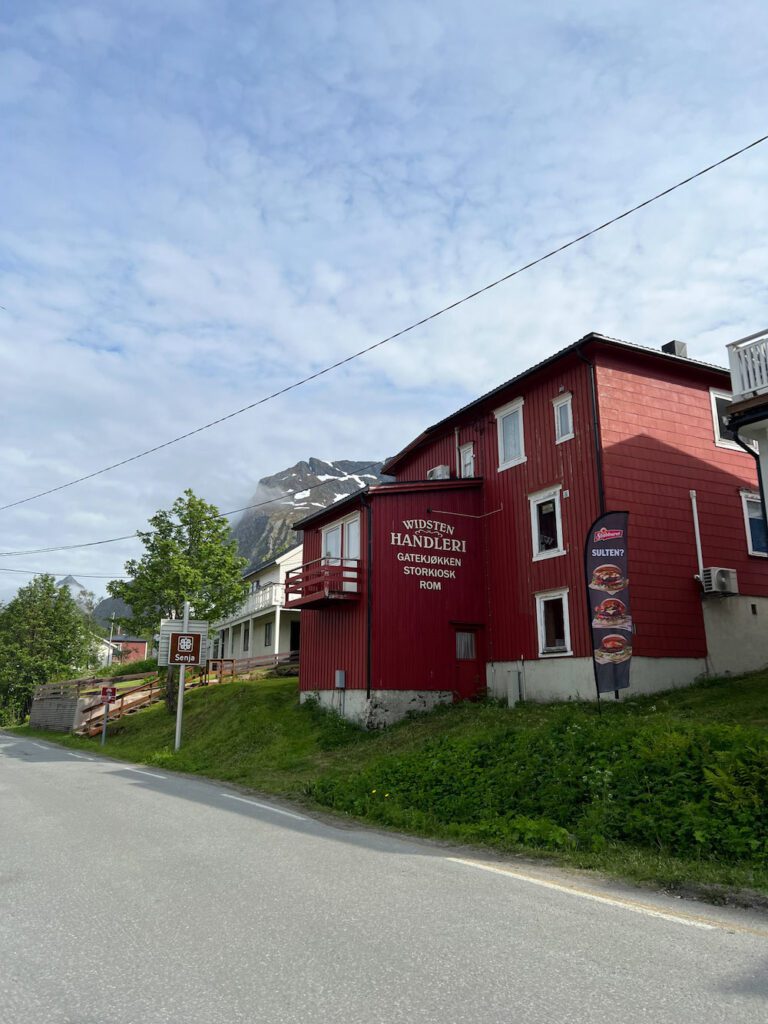 rotes Holzhaus an Strasse mit hohem Berggipfel im Hintergrund