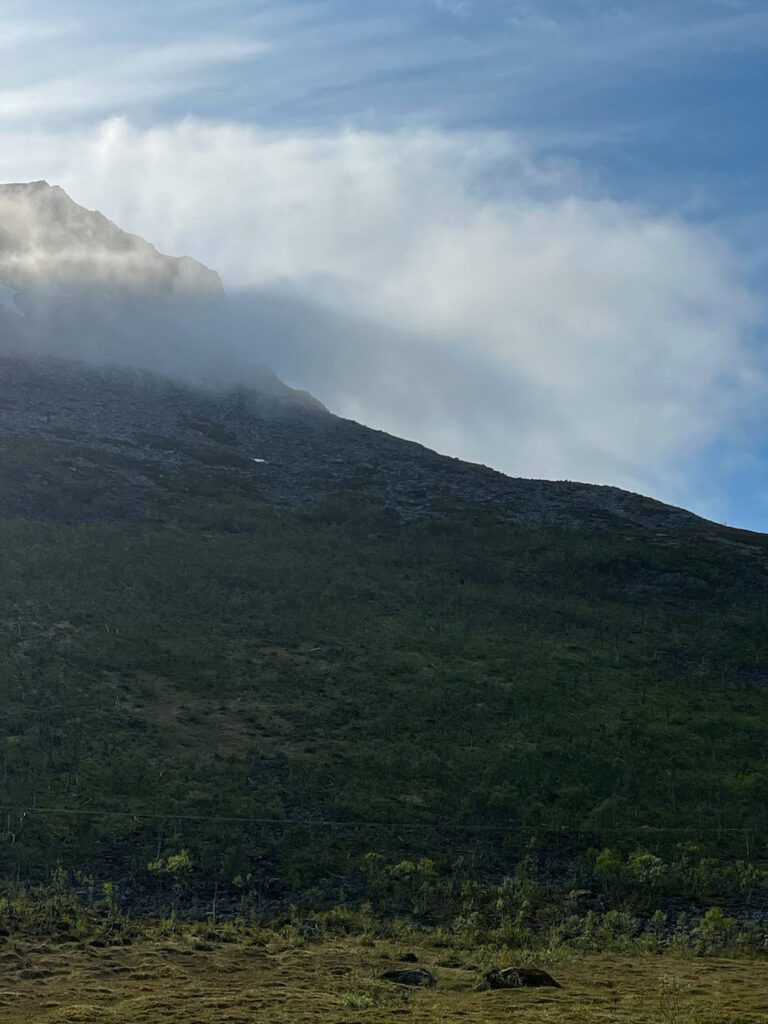 Berggipfel im Schatten, vor einer Wolke umhüllt