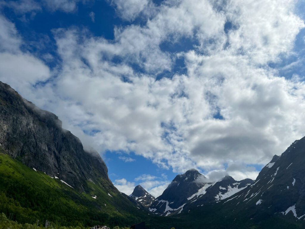 Sehr hohe Berggipfel, zum Teil mit Schnee bedeckt und weiße Wolken vor blauen Himmel