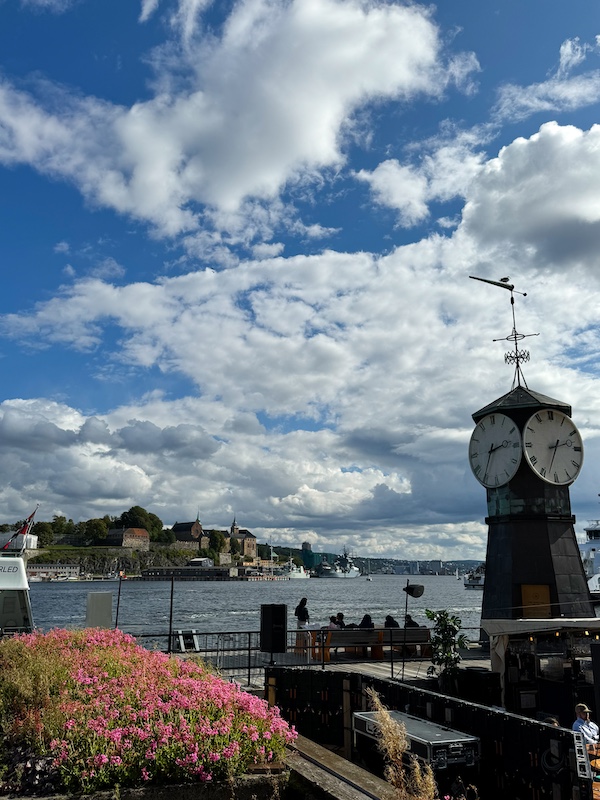 Blick auf Akershus Festung von Aker Brygge mit Blumen und Standuhr im Vordergrund