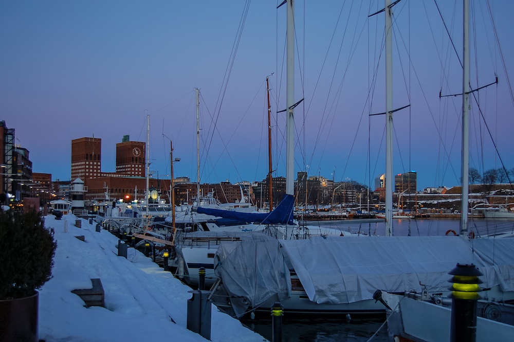 Hafen mit abgedeckten Segelbooten und der Innenstadt im winterlichen Abendlicht