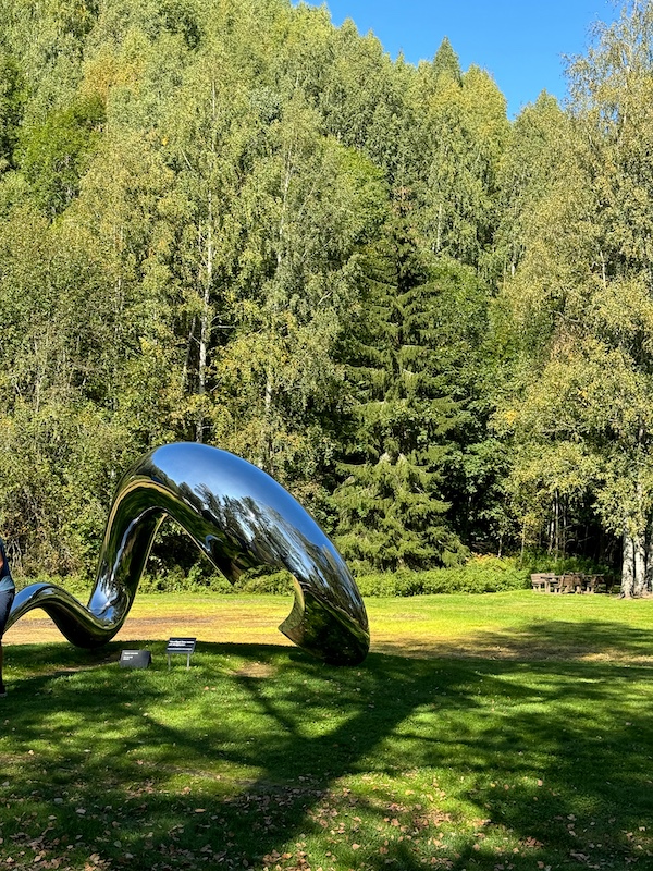 silbernes abstraktes Kunstwerk vor Wald in Kistefos