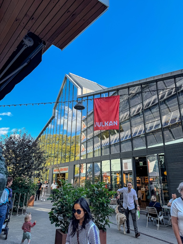 moderne Halle vor blauem Himmel mit vielen Menschen davor